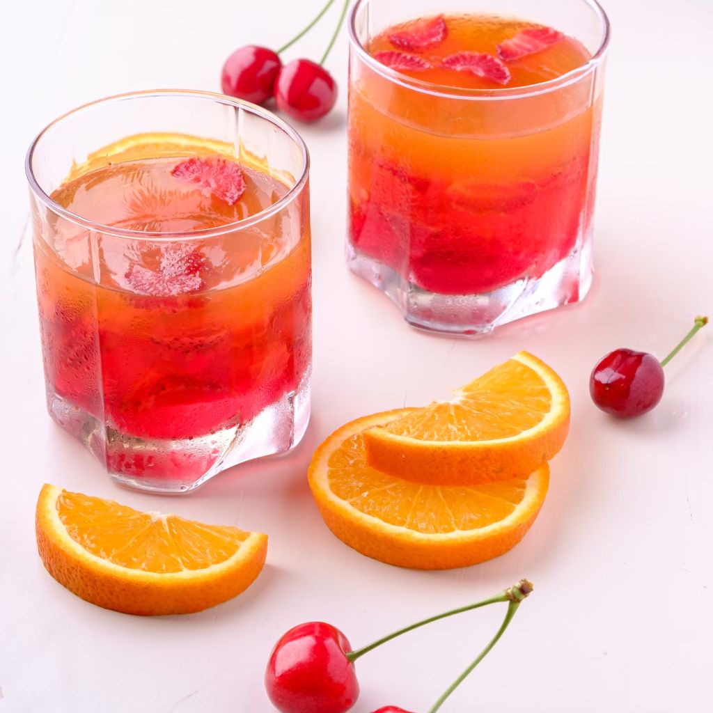 Two Orange And Cherry Drink In Glasses